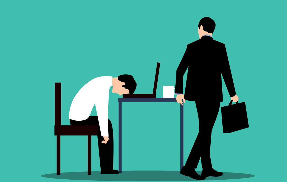 Zdjęcie ilustracyjne: grafika, mężczyną ze zmęczenia trzyma głowę na laptopie